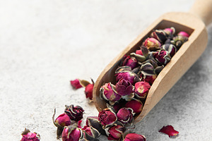 Dried rose buds spilling from wooden scoop, a Food & Drink Photo by Olena Rudo