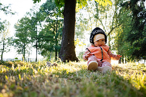 Cute baby sitting in a forest during a warm sunny day, a Photo by AS photostudio