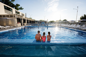 Family enjoying relaxation by the swimming pool during a sunny day outdoors, a Photo by AS photostudio