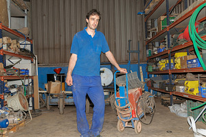 Factory worker moving equipment cart in warehouse, an Industrial Photo by Davizro's Market