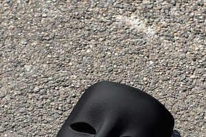 A black mask mockup lying on a textured gray surface, symbolizing mystery or an, a Mask Mockup by Textures & Backgrounds
