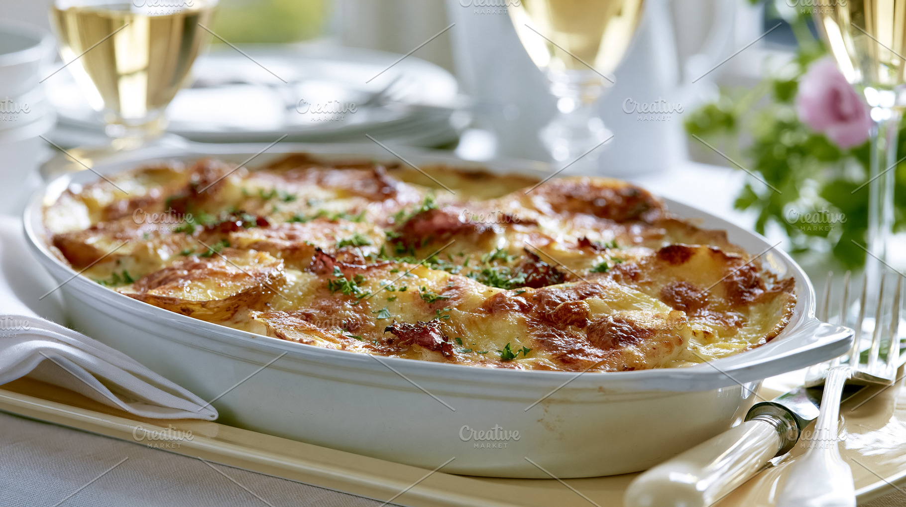 Potato gratin baking in a casserole dish topped with golden cheese and fresh pa, a Photo by Studio ANNA
