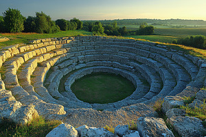 Ancient amphitheater located in a se, a Photo by Tanuart