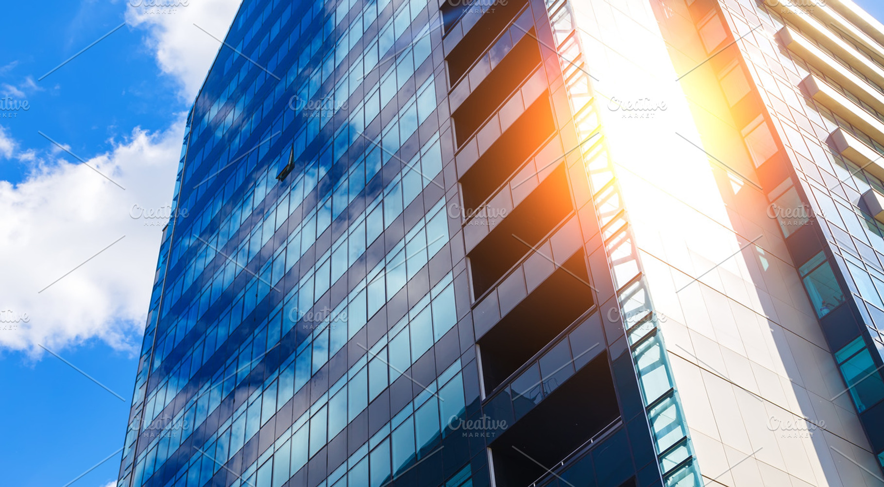 blue glass modern business center in summer with sun behind, a Business Photo by VLADIMIRCARIBB