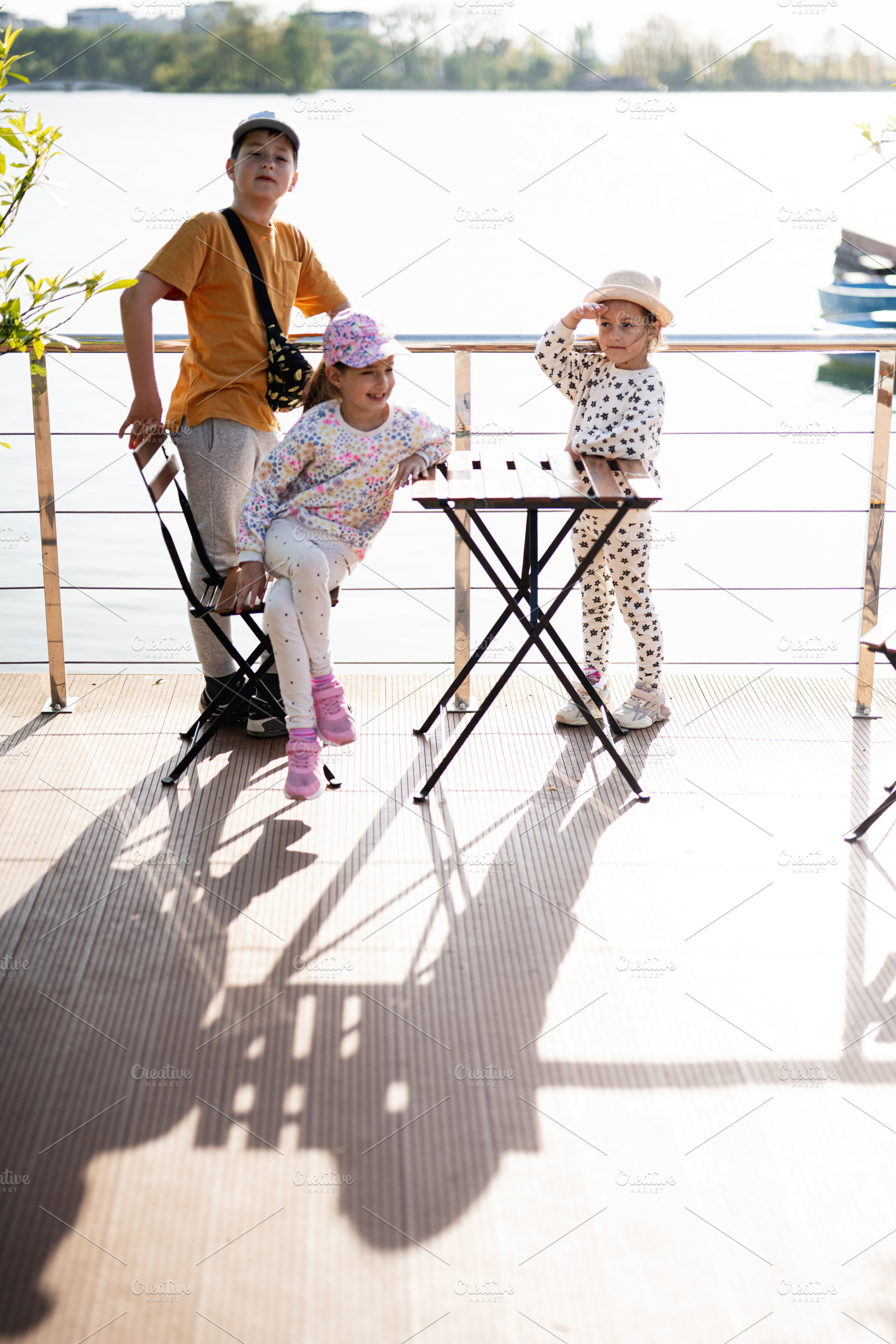 Children outdoors enjoying a sunny day by the water on a wooden deck, a Person Photo by AS photostudio
