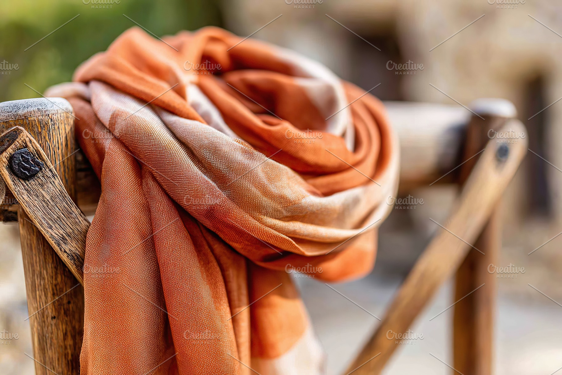 Hand-dyed silk scarf draped elegantly on rustic wooden railing under natural li, a Photo by AlyaAnd