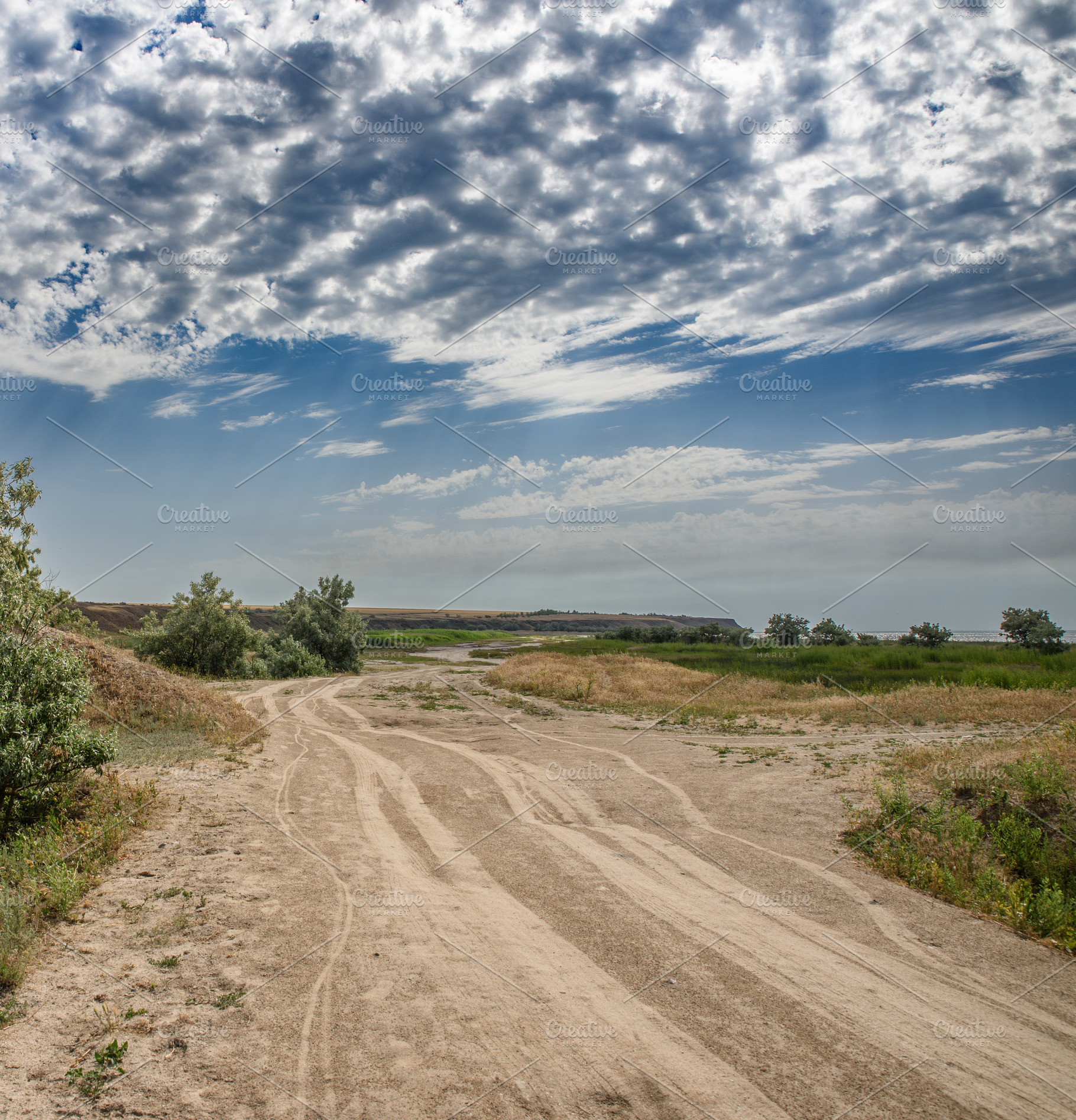 A dirt sand road runs through a flat landscape in the middle of, a Nature Photo by ndanko