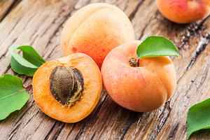 Apricots and its cross-section on the old wooden table.