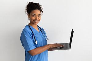 Portrait of black female medical practitioner holding laptop, a Photo by Prostock-Studio