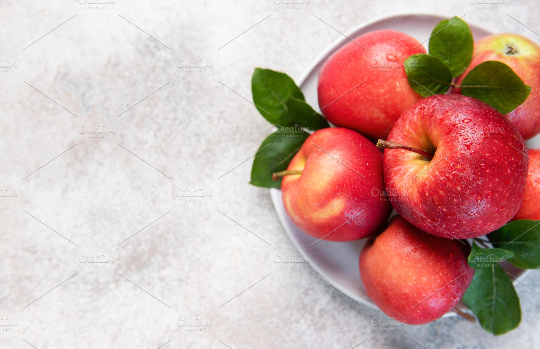 Fresh red apples with green leaves on white plate, a Food & Drink Photo by Olena Rudo