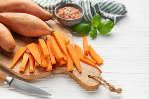 Cutting sweet potato slices for homemade fries on a wooden board, a Food & Drink Photo by Olena Rudo