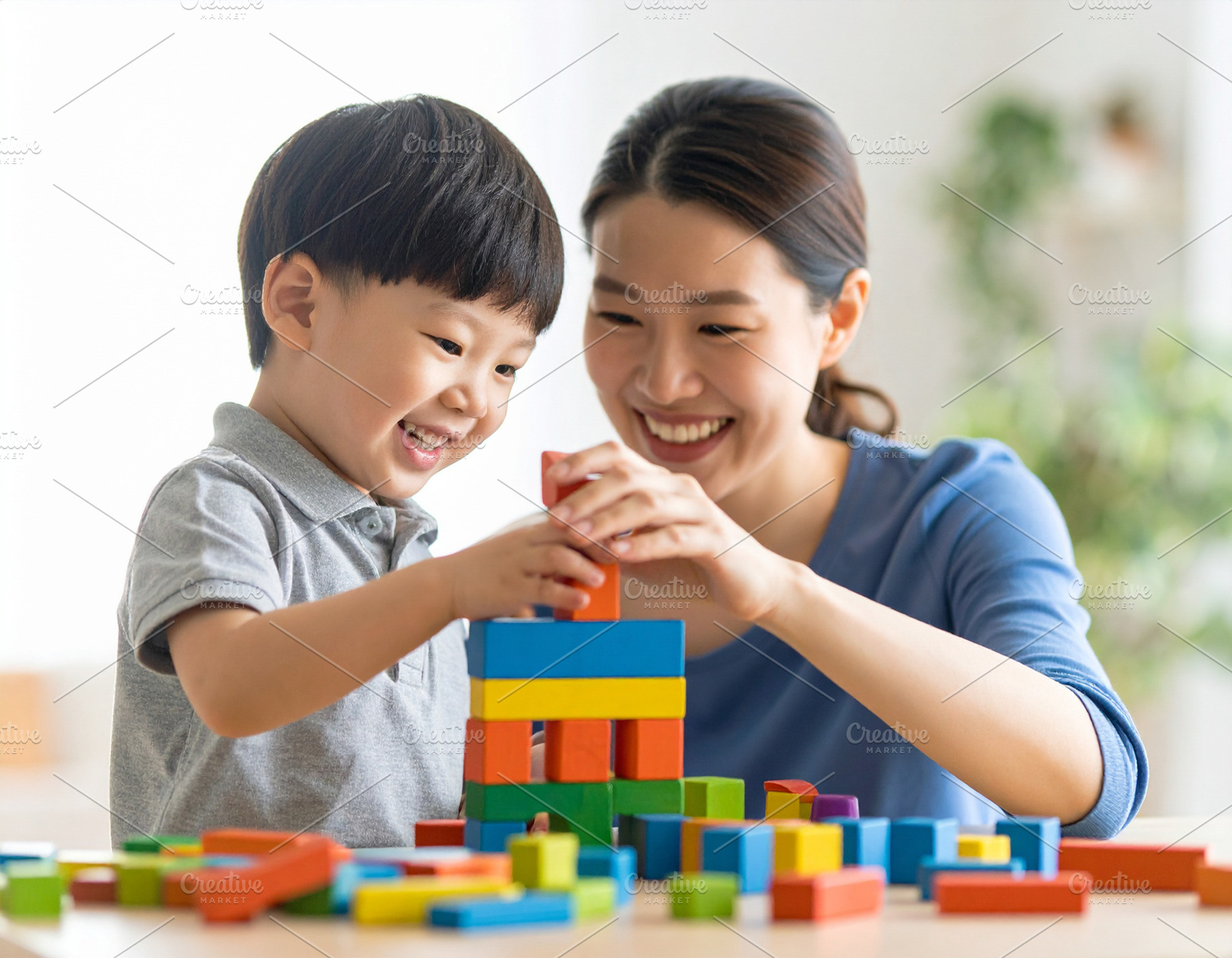Child building with blocks under supervision of a smiling adult, a School & Education Photo by DanFLCreativo