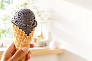 Black sesame ice cream cone in a han, a Photo by Dvoevnore photos