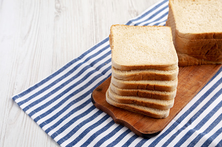 Slices of White Bread on a Rustic Wooden Board, side view. Space, a Food & Drink Photo by LiudmylaChuhunova