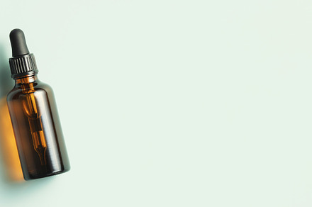 Amber glass dropper bottle with black lid on green background. S, a Beauty & Fashion Photo by Natalia Klenova's Shop