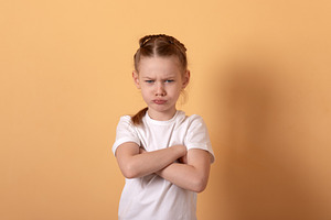 Young girl with braided hair standing against a beige background, a Person Photo by Ales Munt