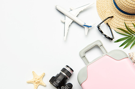 Pink suitcase, camera, sunglasses and airplane model suggesting