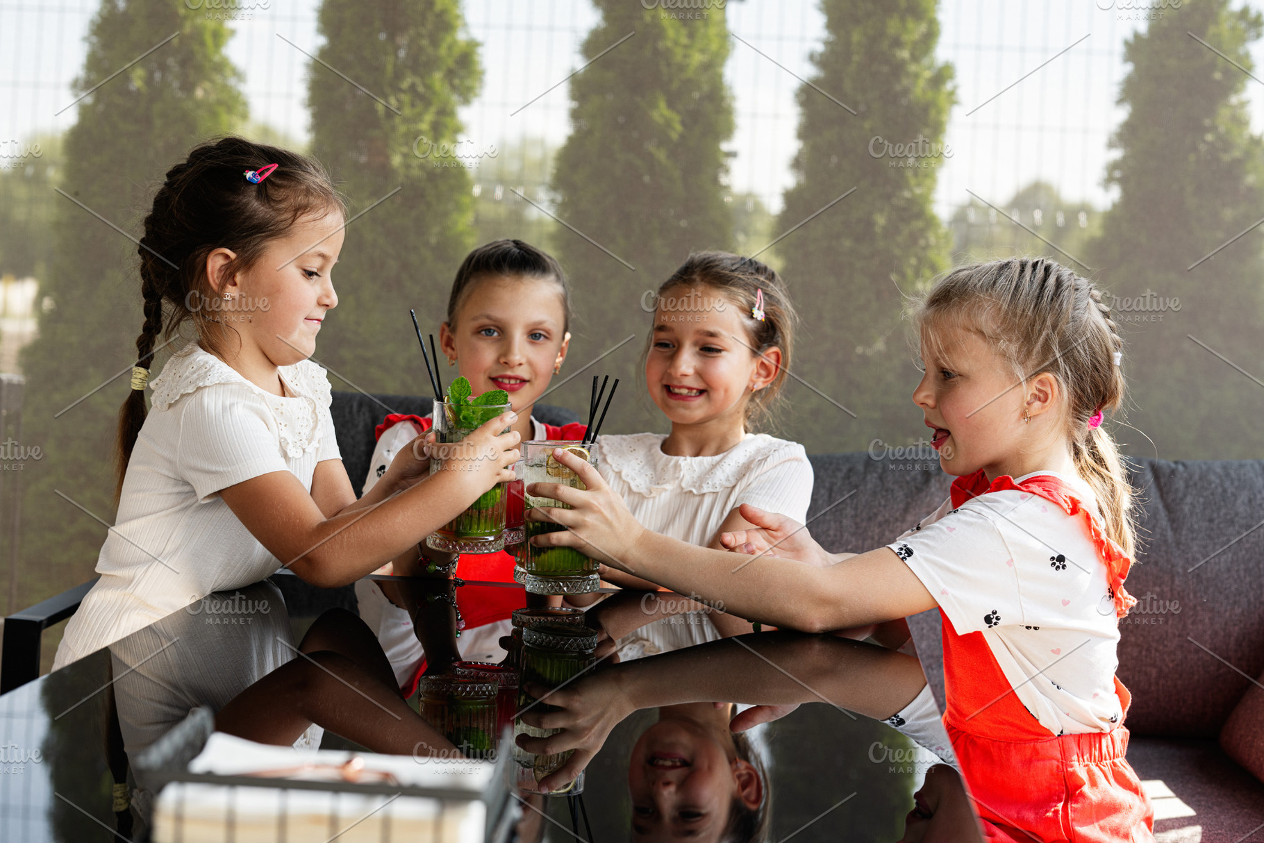Four young friends enjoy refreshing drinks together at an outdoor gathering, a Photo by AS photostudio