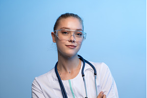 Female doctor wearing goggles, ready, a Health & Medical Photo by volodymyrshtun13795