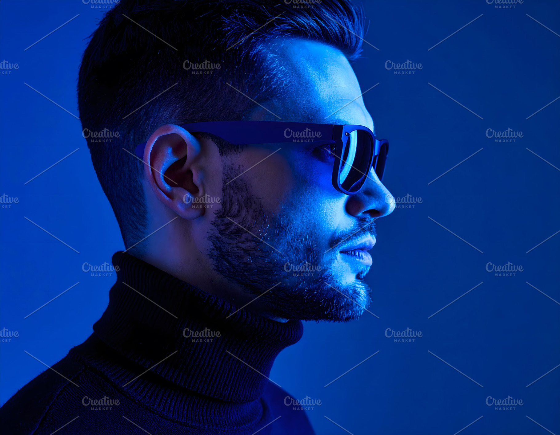 Businessman wearing sunglasses in blue studio creative lighting, a Person Photo by GoodGoods