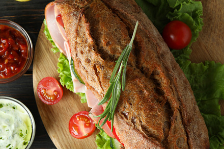 Board with ciabatta sandwich and ingredients on wooden table, a Food & Drink Photo by AtlasStudio PRO