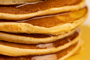 a tower of small milk pancakes on a ceramic bowl with natural yellow bee honey, a Photo by rsoollAI
