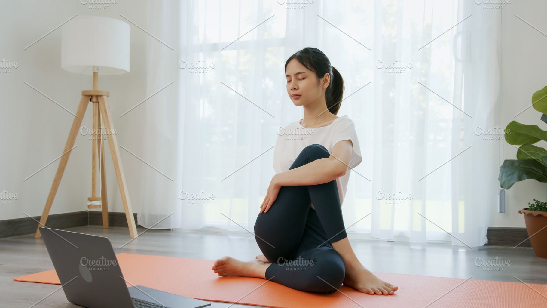 Asian women doing yoga exercises by themselves and watch video tutorials online, a Sports & Recreation Photo by sitthiphong