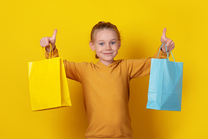 Smiling young girl in hoodie holding colorful shopping bags and, a Person Photo by Ales Munt