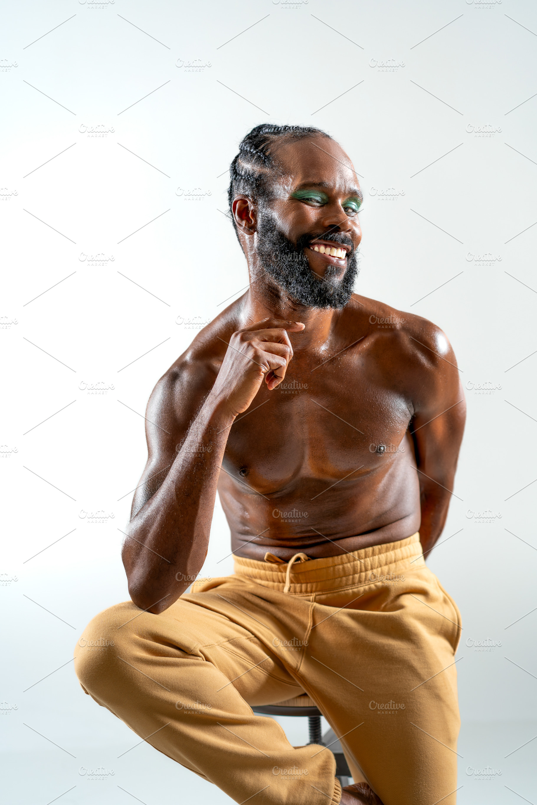 Happy black shirtless gay model sitting on stool in white studio, a Person Photo by andreonegin market