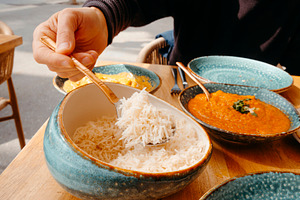 man taking some rice from a bowl, a Photo by Nito