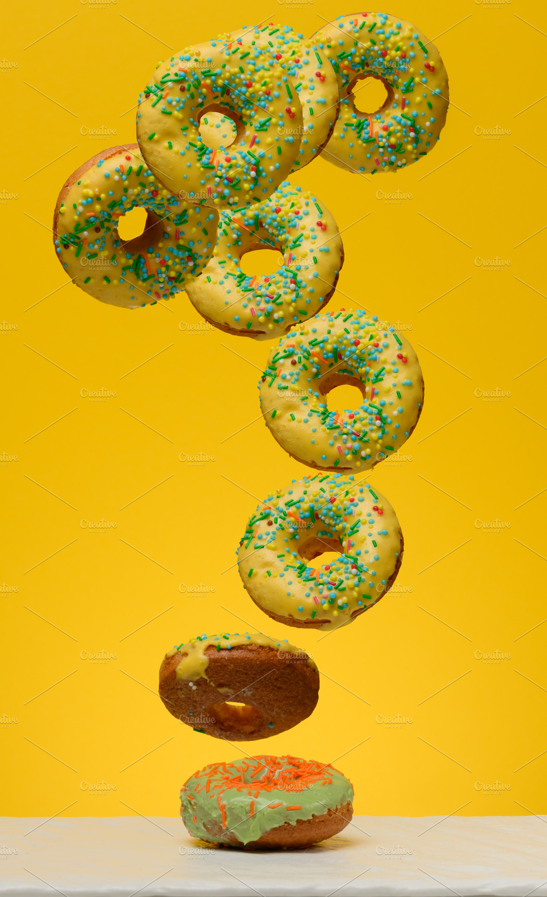 Yellow glazed donuts, each decorated with multi colored sprinkle, a Food & Drink Photo by ndanko