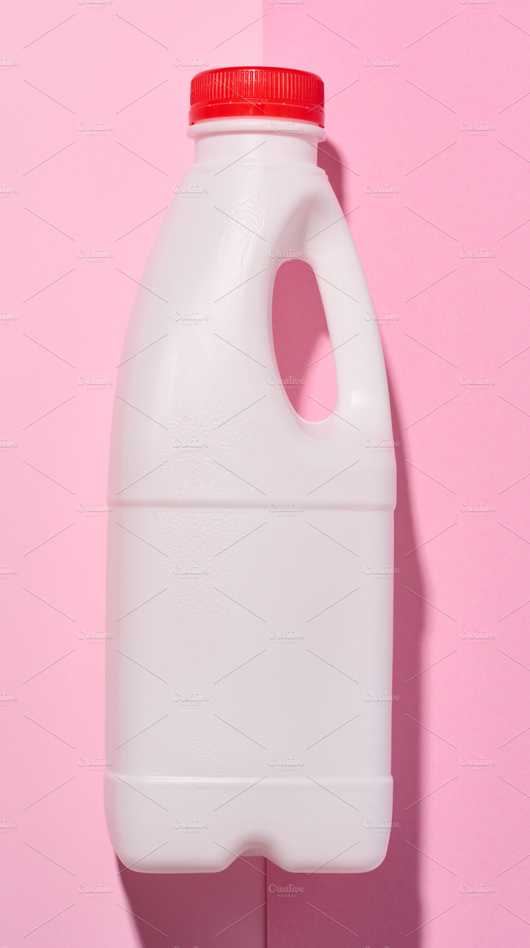 White plastic bottle for milk and dairy products on a pink backg, a Food & Drink Photo by ndanko