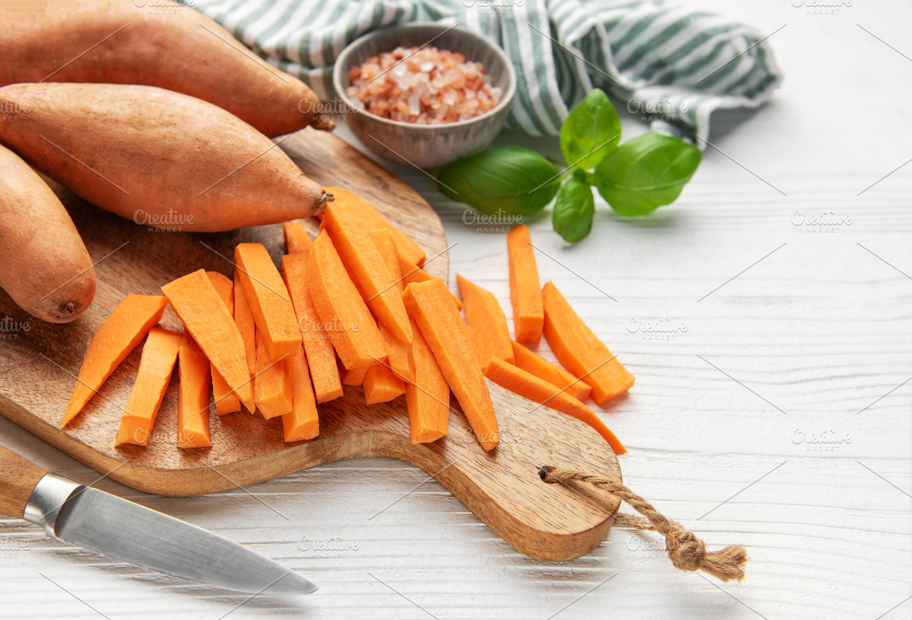 Cutting sweet potato slices for homemade fries on a wooden board, a Food & Drink Photo by Olena Rudo