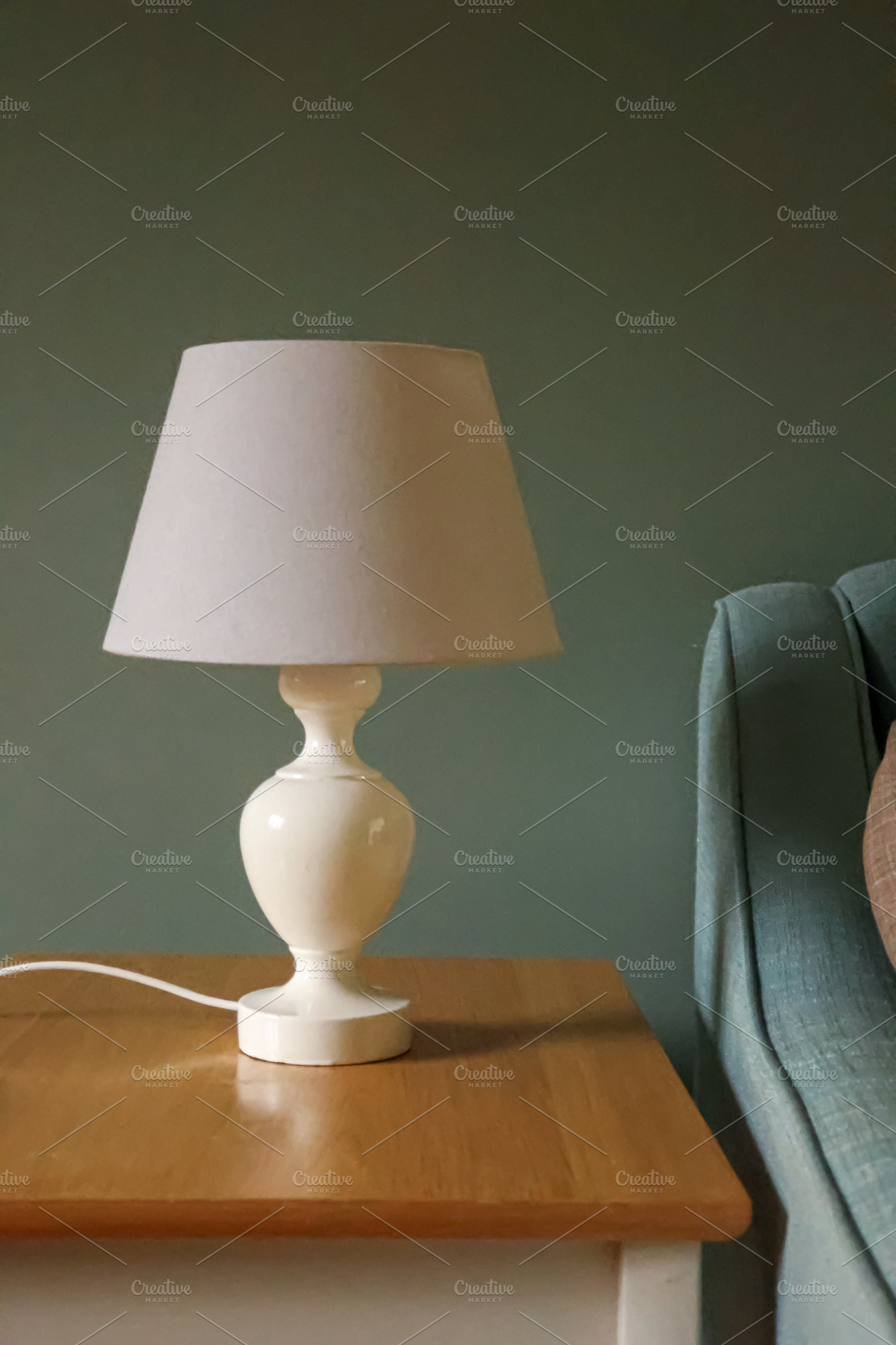 White lamp on wooden side table providing cozy, ambient light in, a Photo by Studio ANNA