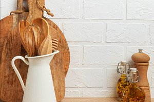 Kitchen utensils resting on wooden countertop by white brick wal, a Food & Drink Photo by Olena Rudo