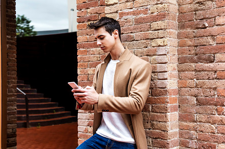 Handsome man wearing a coat standing outdoors, holding mobile phone, a Person Photo by 2Design