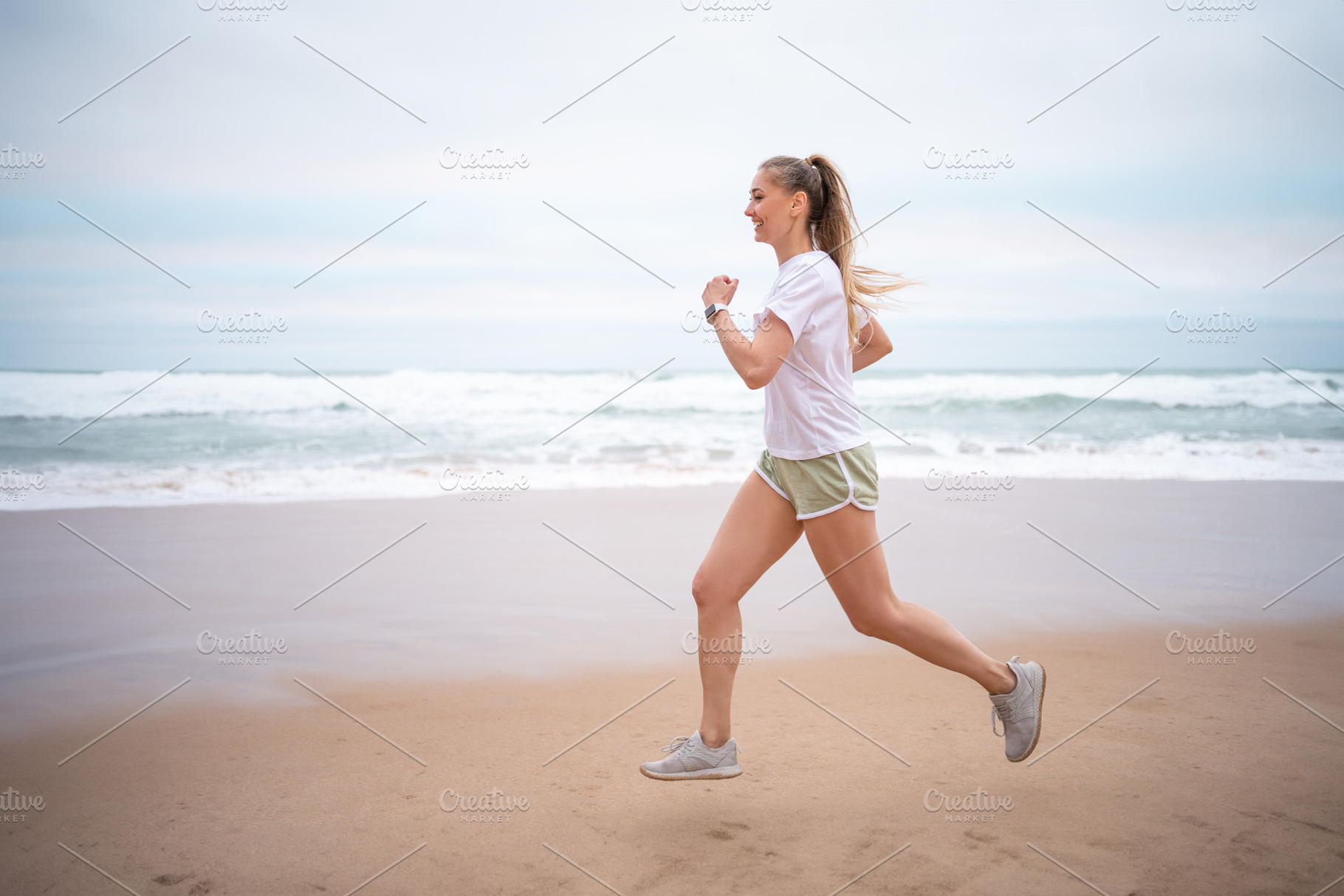 Happy sporty woman jogging on wet seashore against sky at beach, a Person Photo by andreonegin market