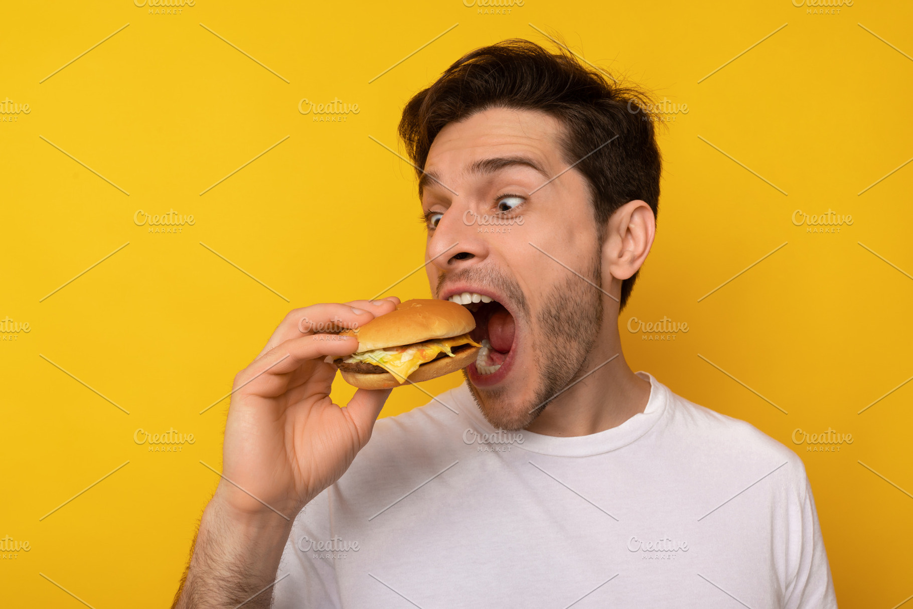 Funny Guy Holding Burger Biting Sandwich At Studio, a Photo by Prostock-Studio