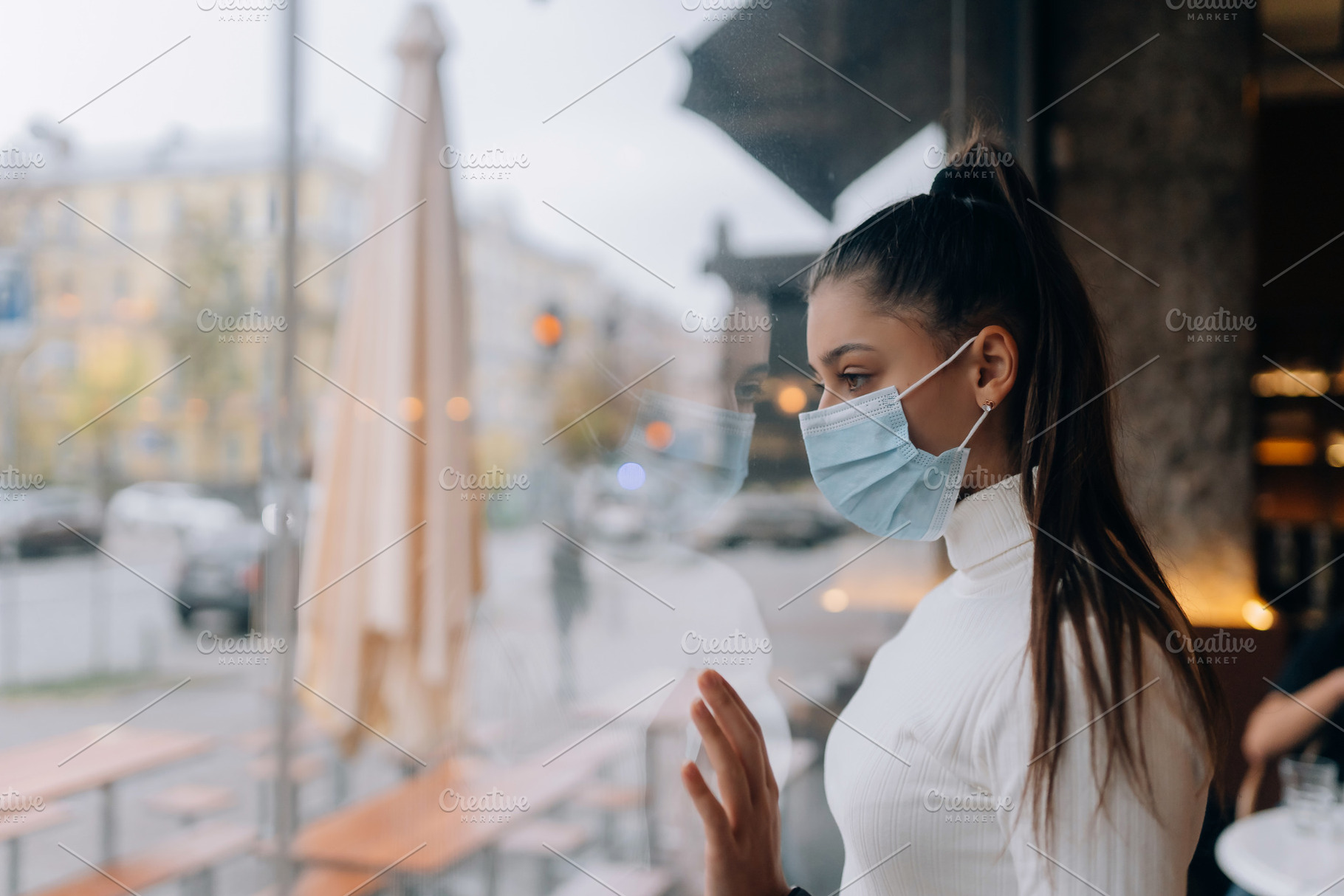 Young woman in face mask standing in front of windows in cafe., a Person Photo by Tekso