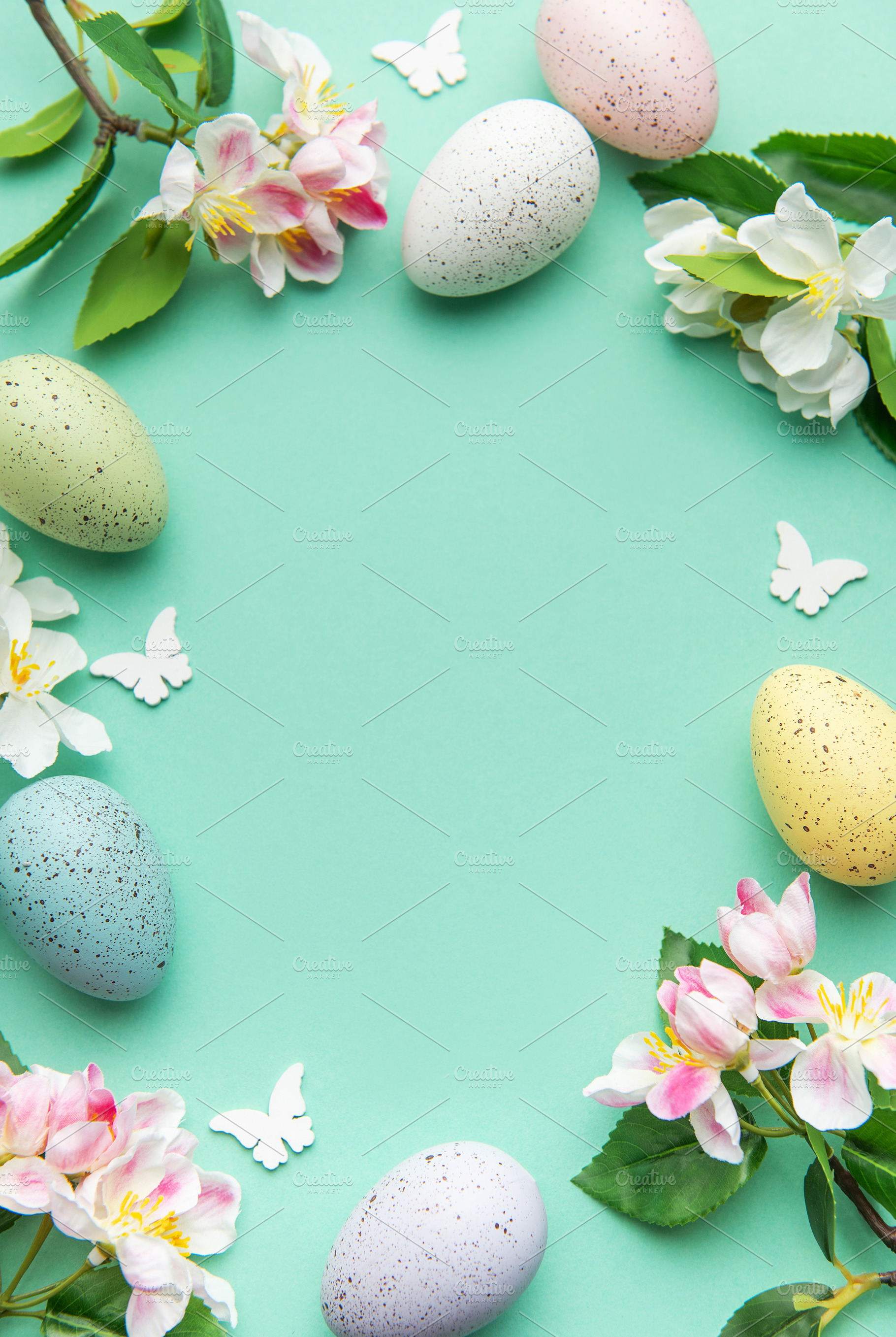 Easter eggs and spring flowers creating a frame on a turquoise b, a Holiday Photo by Olena Rudo