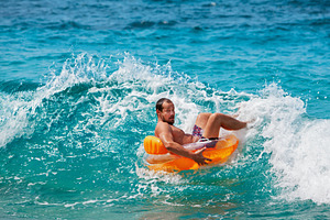 Funny man riding on tubing on wave