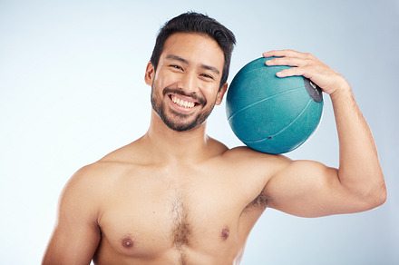 Man, studio and fitness with smile, medicine ball and happiness for wellness, muscle and training goal. Model bodybuilder, portrait and happy with workout ball, exercise and body beauty by background, a Photo by Peopleimages.com