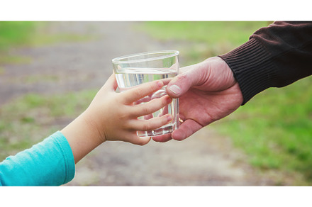 The father gives the child a glass, a Food & Drink Photo by yanadjana