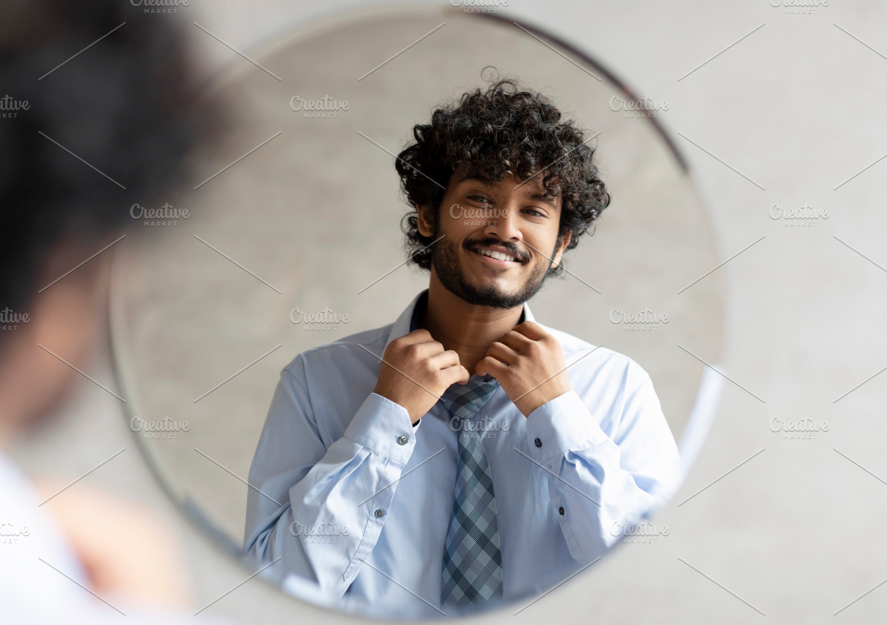 Excited indian businessman getting ready and buttoning up shirt, standing in ba, a Person Photo by Prostock-Studio