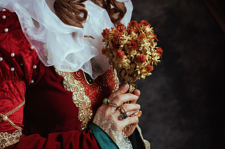 Closeup on medieval queen in red dress with dried flower, a Person Photo by Alliance Images