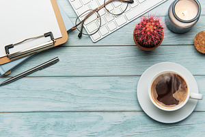 Office desk with coffee, keyboard, and supplies on light blue wo, a Business Photo by Olena Rudo