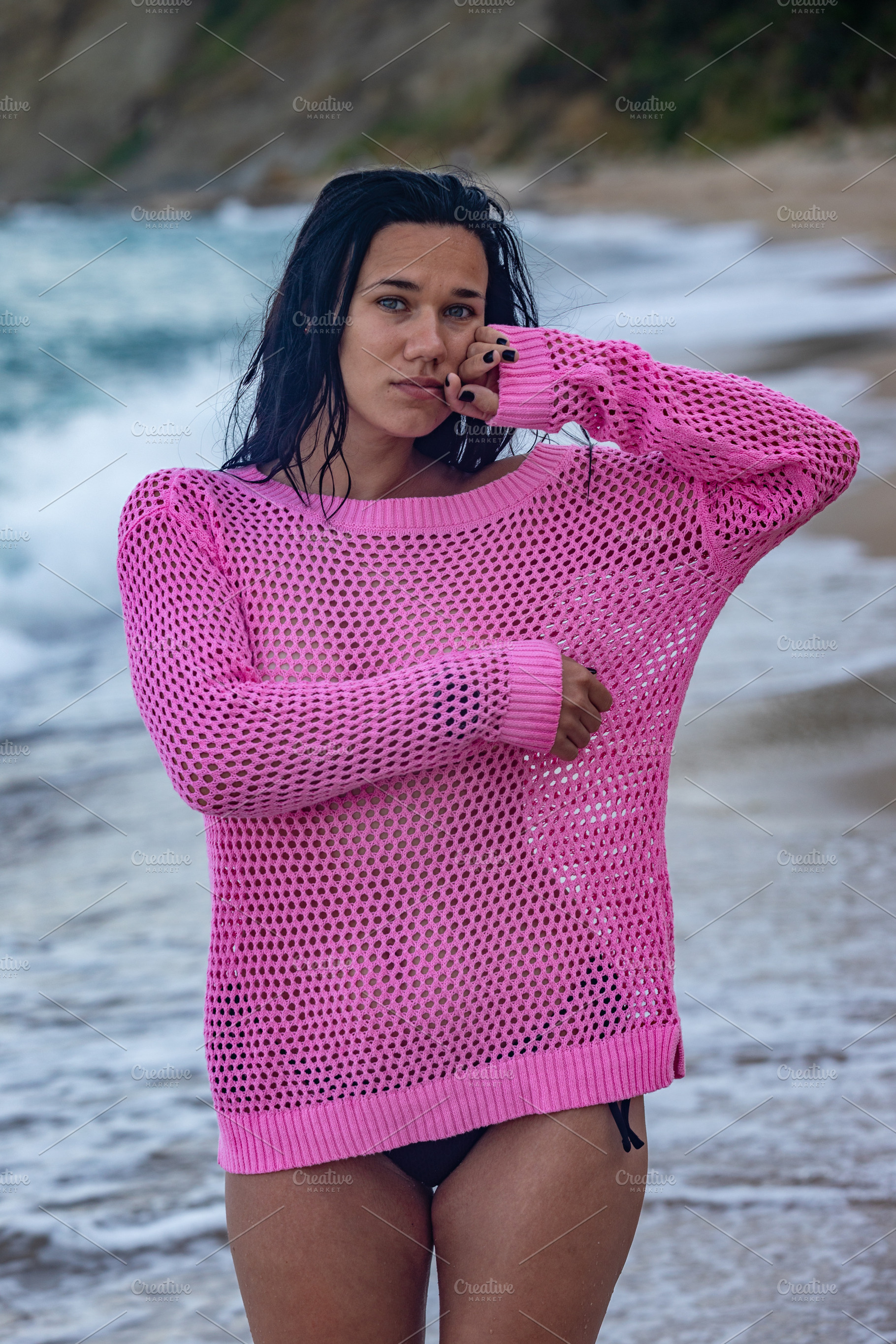 Young woman in a vibrant pink sweater and black bikini standing on a scenic bea, a Person Photo by Ales Munt