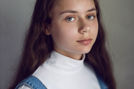portrait of a serious Caucasian teenage girl in a white T-shirt against a gray, a Person Photo by SaulichPhoto