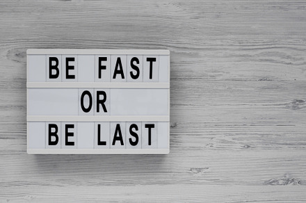 'Be Fast or Be Last' on a lightbox on a white wooden background,, a Business Photo by LiudmylaChuhunova