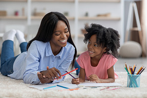 Loving african american mother and daughter painting together, a Photo by Prostock-Studio